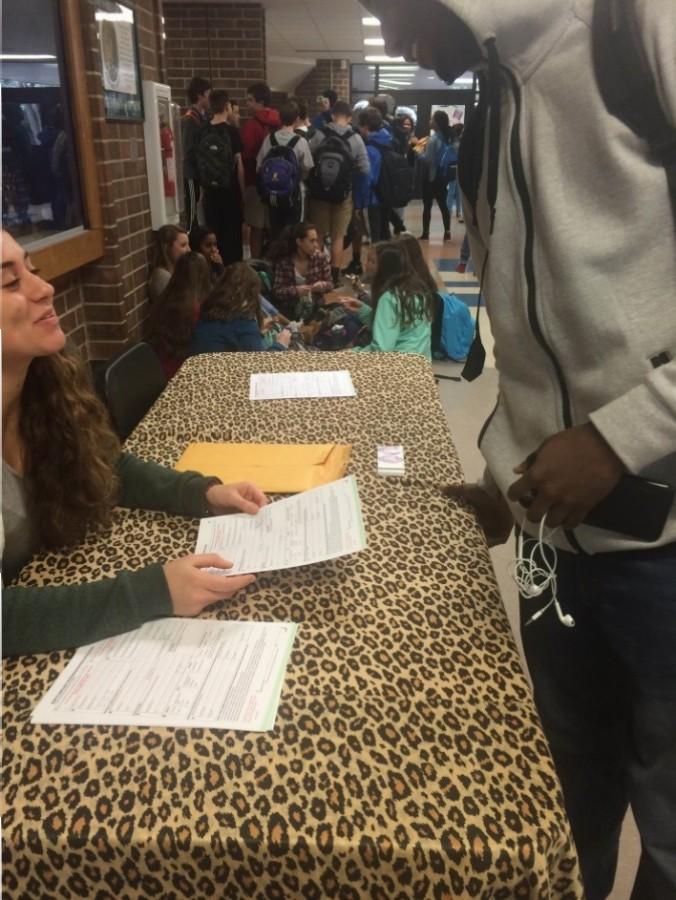 Elena Price hands student a voter registration sheet