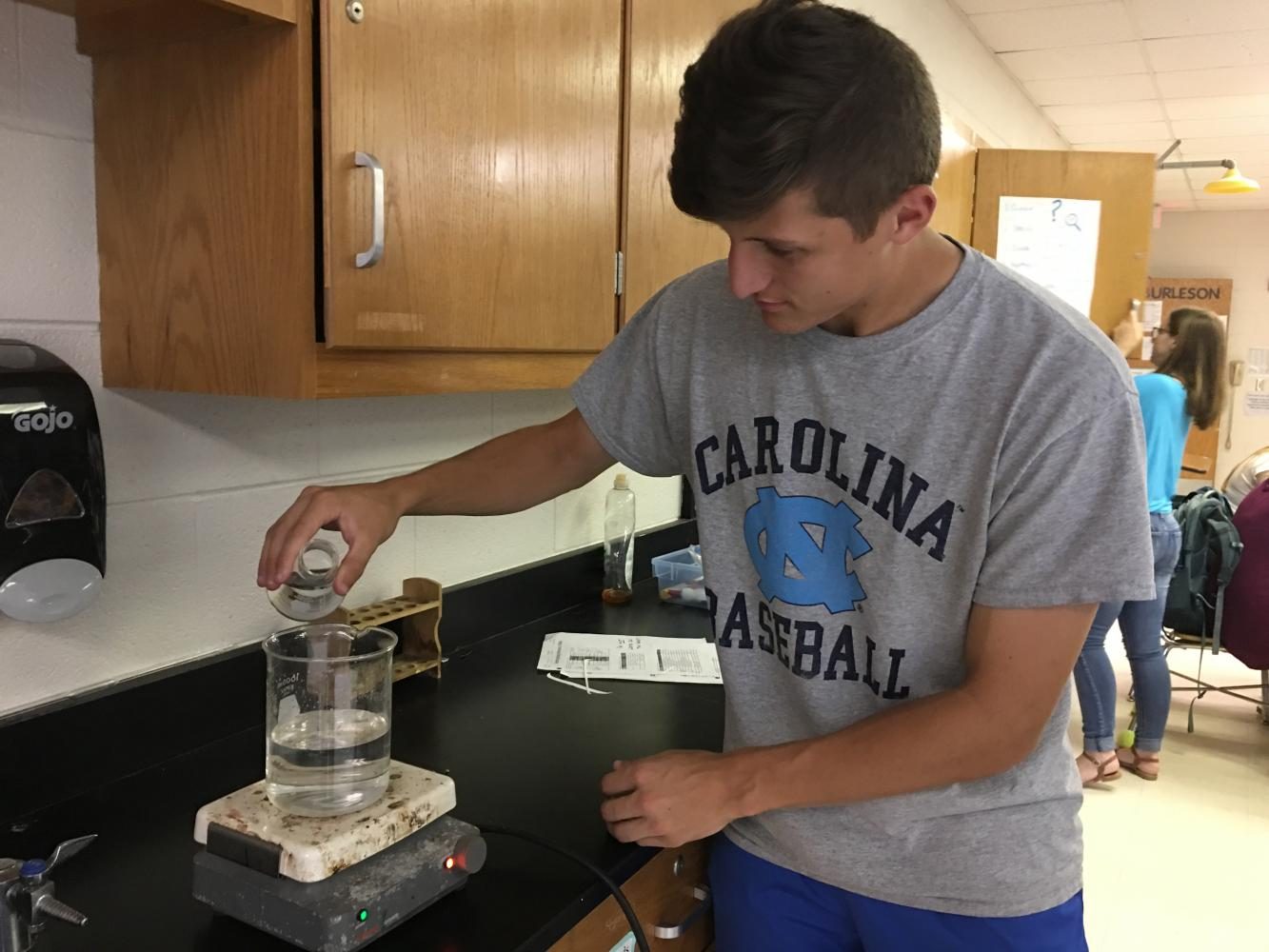 Sam Ender pouring hydrochloric acid into a beaker of water in preparation for his demo lab in chemistry on May 17, 2017.