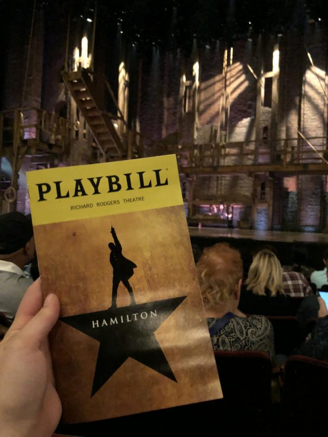 A Hamilton playbill is held up in front of the Richard Rodgers Theatre in New York City