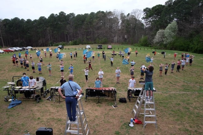 Jerome Markoch is shown teaching marching band outside of the classroom, with masks being required and separation of students to ensure their safety. 