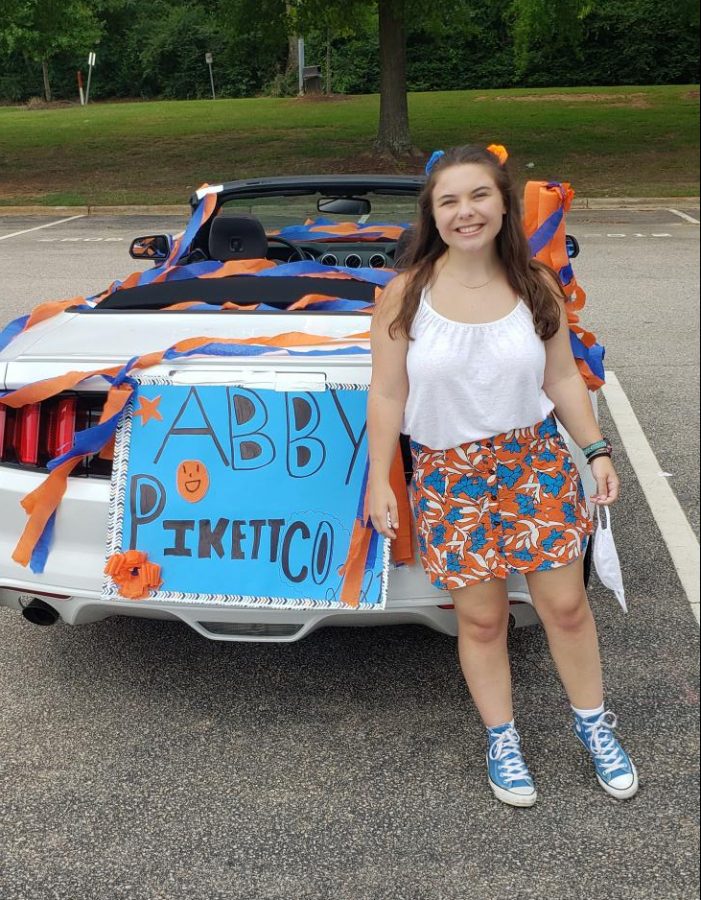 Senior Abby Pikett stands next to her decorated car at the Senior Drive Through at Athens Drive.