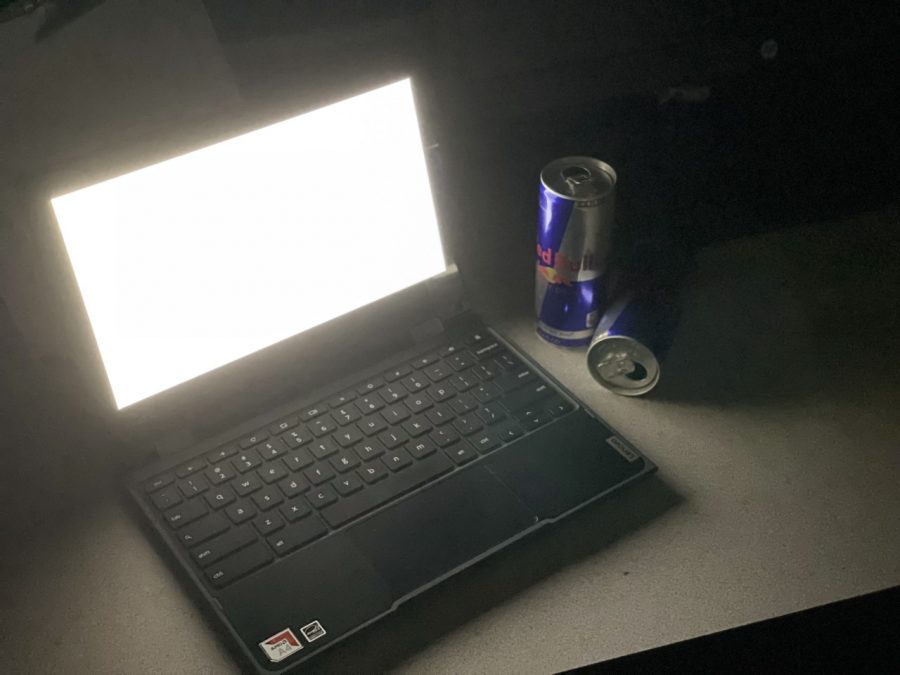 A+blank+white+screen+with+two+Red+Bull+cans+next+to+it+in+a+dark+room.+