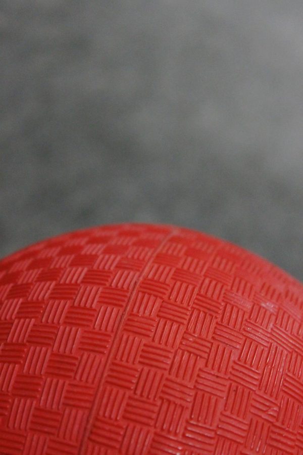 A bright red dodgeball that is prepared to be used in a dodgeball game.