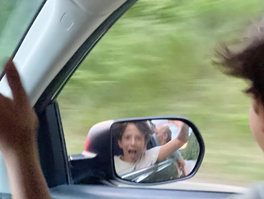 Kid+yelling+out+car+window+on+warm+August+evening.+Wind+in+hair+excitement+in+face.