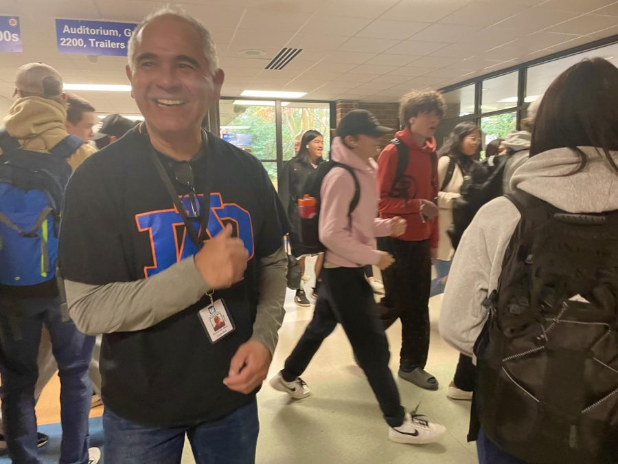 Fernando Ruiz smiles after talking with students in the hallway. Pictured wearing an Athens Drive T-shirt, he is always representing and supporting the school.