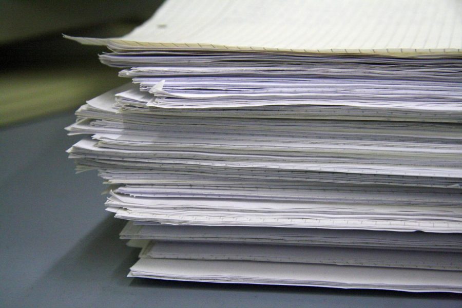 A photo that shows a stack of many papers pushed to the side. This symbolizes procrastination and the act of pushing one's work to another day. 