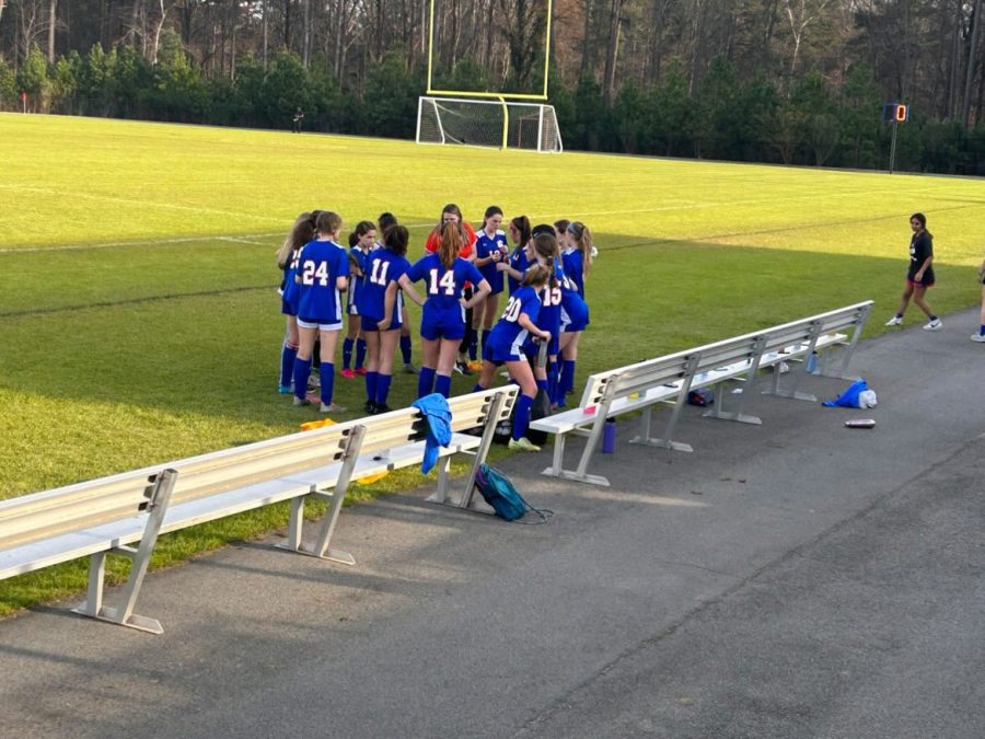 Womens JV soccer gathers in a huddle to discuss their game strategy.