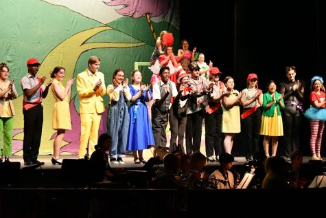 The cast take their final bows at the end of the show. The pit is seen as they play off the last song. 