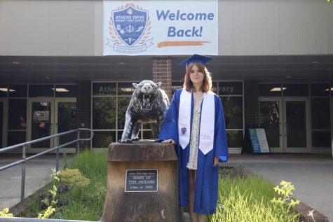 Karolina Luik posing with the jaguar statue outside of Athens Drive high school, in her graduation gown. 
