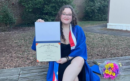 Crystal McCabe, a recent graduate, poses outside Athens Drive High School. She is one of many graduates celebrating at the Mid-Year Graduation.