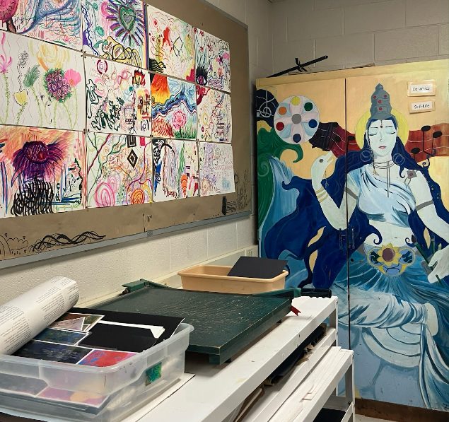 A corner of the room in Erin Days art class. There is multiple students artwork on the wall and materials.