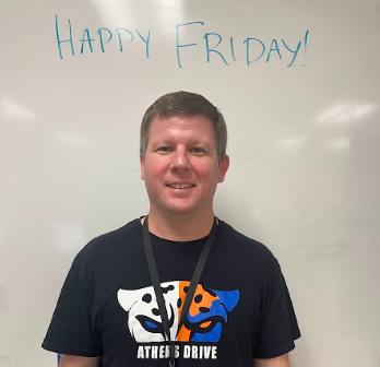 Mr. McGirt poses for a photo in front of his whiteboard. “Happy Friday!” written above him as motivation to his students.