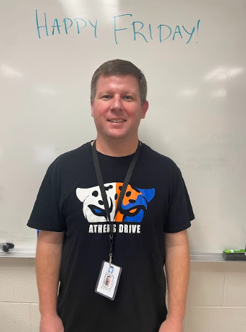 Mr. McGirt poses for a photo in front of his whiteboard. “Happy Friday!” written above him as motivation to his students.