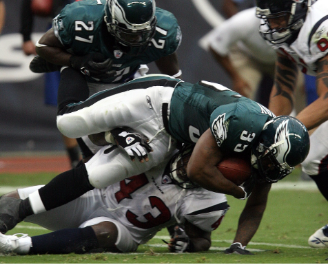 Running Back on the Philadelphia Eagles getting tackled by the opposing team. 