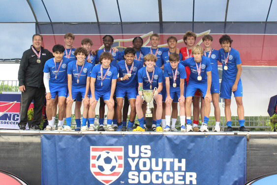 Nathan Kogi and his team celebrated their victory at the US Youth Soccer Championship! Through teamwork and determination, they proudly wear their medals and hold their trophy. A proud moment for Kogi and his teammates