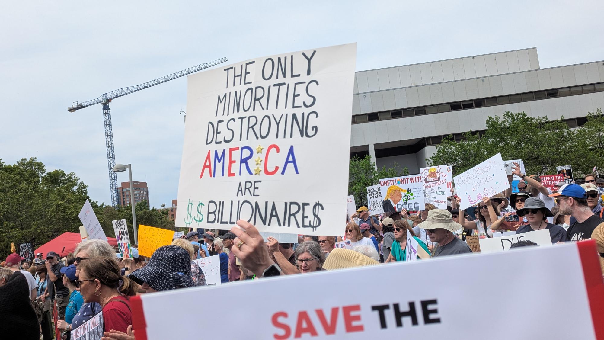 A large group of protesters at the Raleigh April 19th "Forward Together" protest. A protest sign in the middle reads "the only minorities destroying America are billionaires"