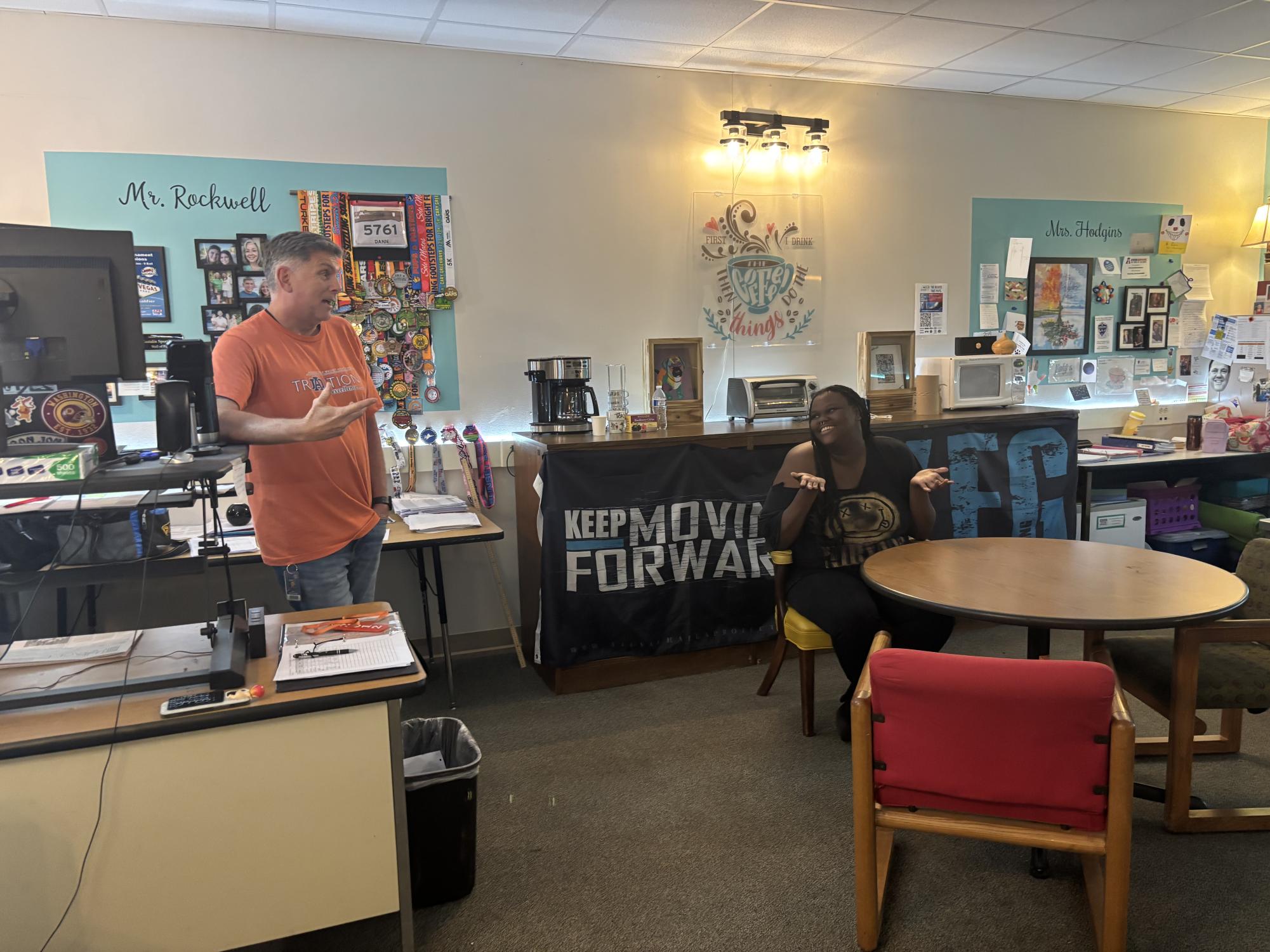 Mia McClamb and Dann Rockwell conversing in his office. 
